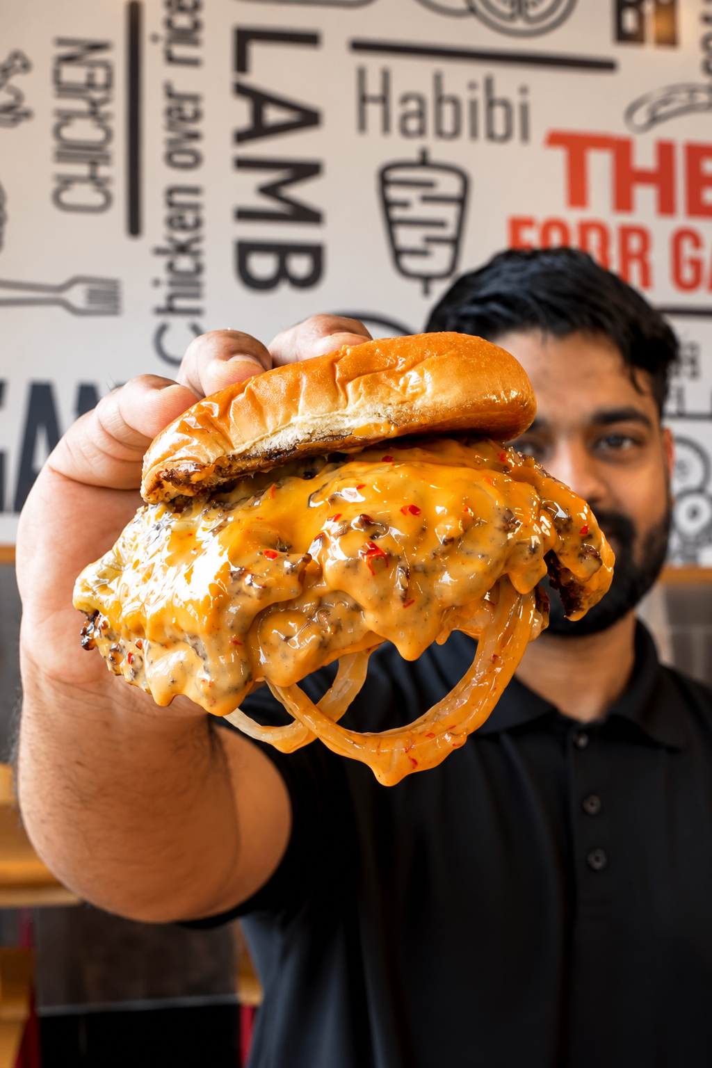MF team member presenting a burger inside MF Gyros & Burgers