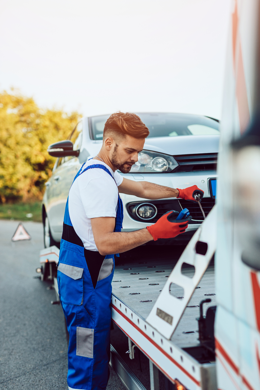 Tow operator securing a disabled vehicle on a flatbed truck