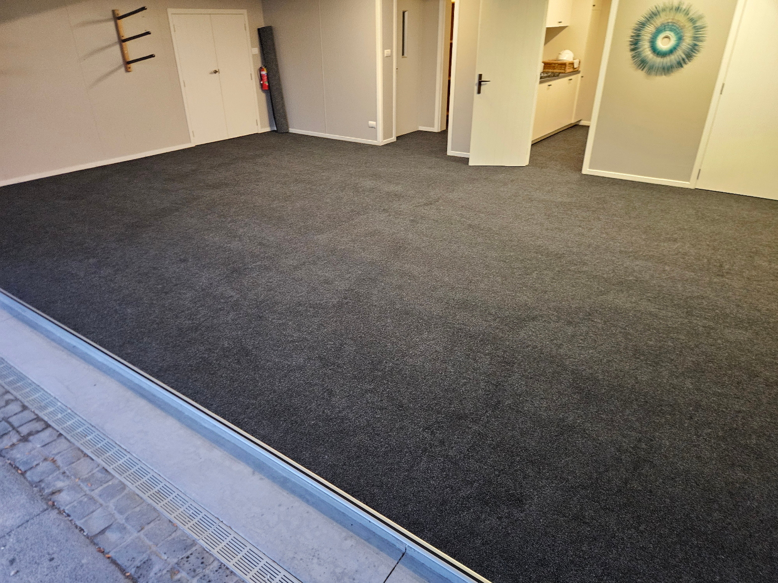Dark grey carpet freshly installed across a large garage conversion space