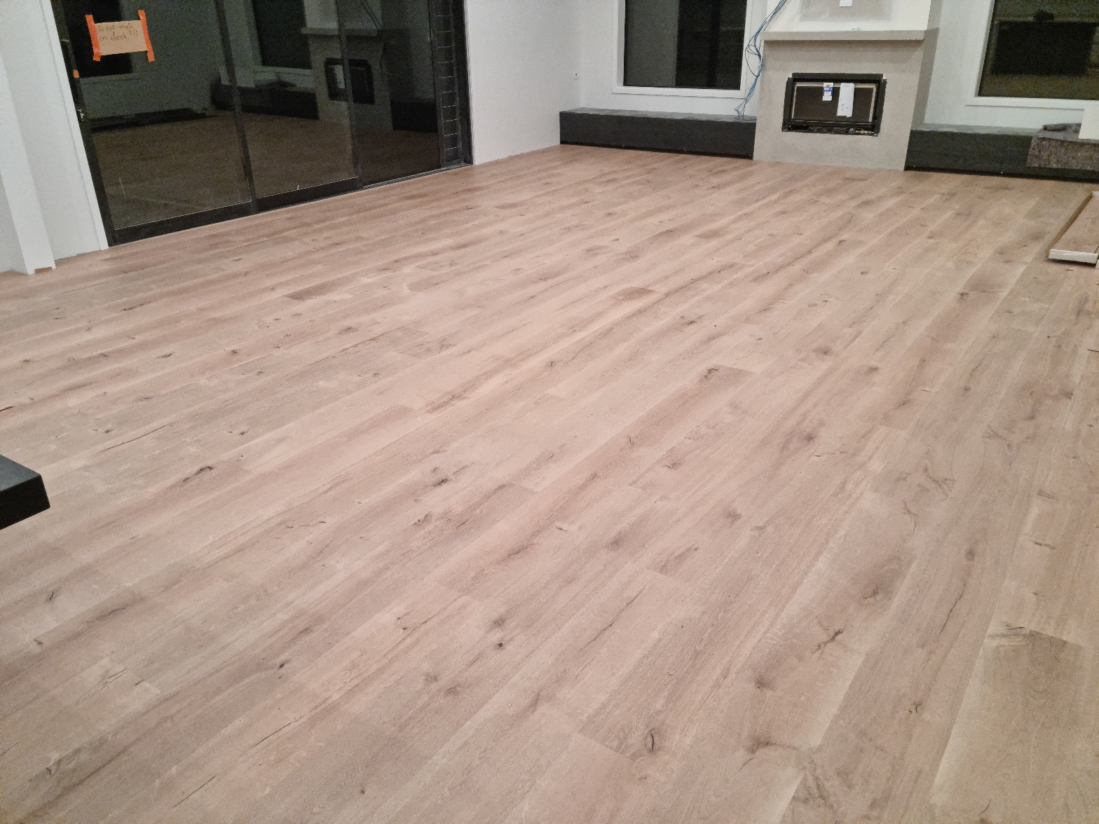 Sandy beige laminate flooring freshly installed in a bright open-plan living room under construction