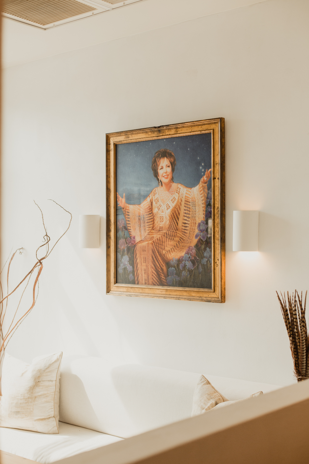 Painting with wall sconces above lounge seating